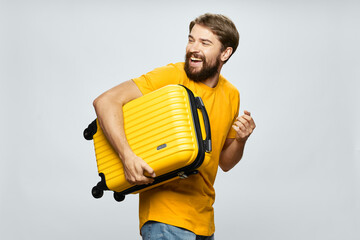 a man with a yellow suitcase walks to the side looking back on a light background