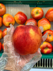 closeup hand wearing transparent glove picking red apple from basket at supermarket, disposable hand glove protect infection during food shopping
