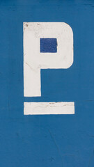 Letra P blanca pintada en pared azul como cartel de parking