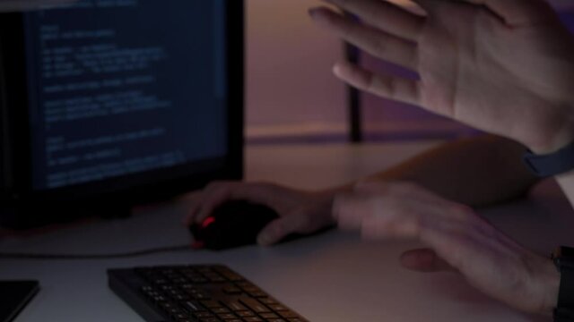 Two worker of IT sphere are discussing new project sitting in front of computer monitor with java script on it in macro. Closeup view of two programmers hands in moment of coding new web site project
