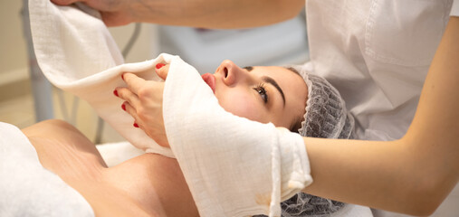 Relaxed young woman lying on spa bed prepared for facial treatment and massage in luxury spa resort. Wellness, stress relief and rejuvenation concept.