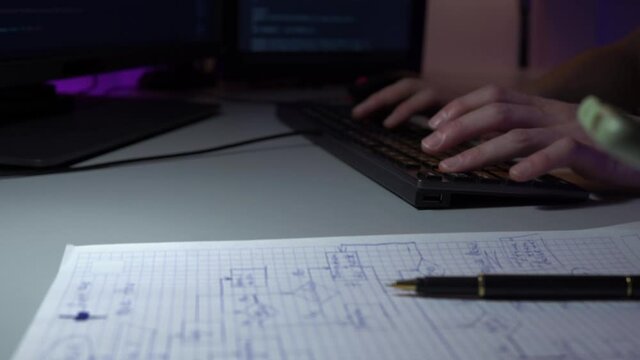 Closeup view of two colleagues working together sitting in front of computer in office. A woman is writing schema and a man is typing new html code lines on keyboard. Team works of programmers concept