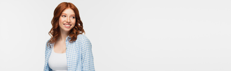 pleased redhead woman in plaid shirt isolated on white, banner.