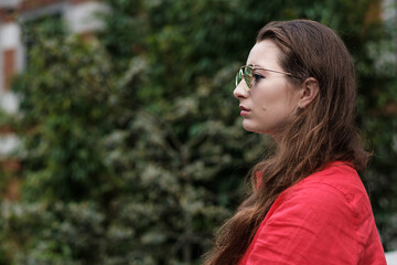 Portrait of young woman in red shirt wearing mirror sunglasses.