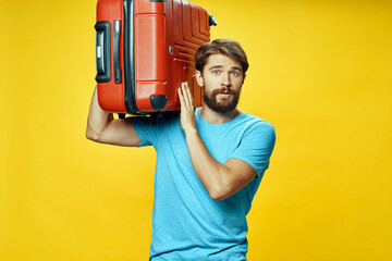 a man in a blue t-shirt in a red suitcase on a yellow background