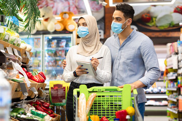 Muslim Spouses Taking Notes In Grocery Shopping List In Supermarket