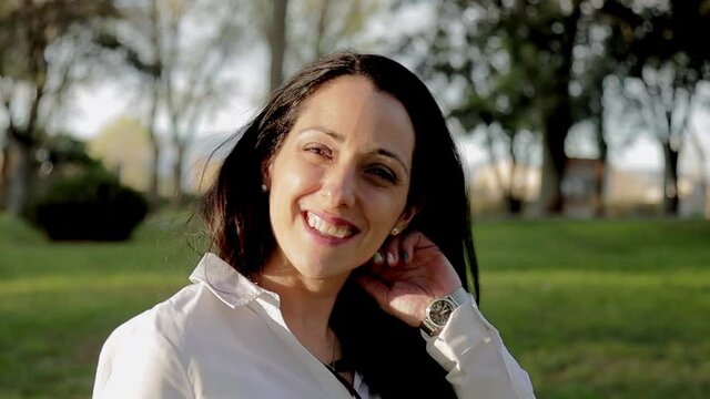 Attractive female smile to camera outdoors during sunset. Pretty brunette woman