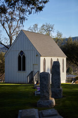 Fototapeta na wymiar Small White Mountain Church in a Cemetery