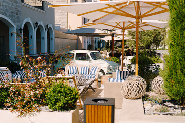 Cozy cafe in Lustica Bay, Montenegro. Wicker furniture with striped pillows, parasols and a retro...