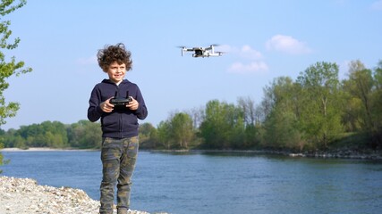 6 year old boy flies with drone in nature near a river - new technology about video 4k and...