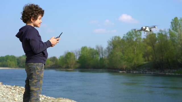 6 year old boy flies with drone in nature near a river - new technology about video 4k and photography 