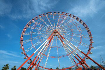 A large red and white Ferris Wheel against a blue sky