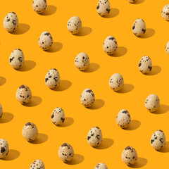 Pattern made of quail eggs on yellow background. Minimal Easter food concept.