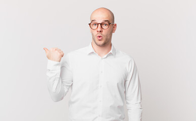 bald man looking astonished in disbelief, pointing at object on the side and saying wow,...