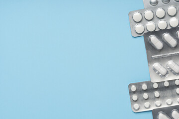 Packs of white pills on blue background, top view. Different medicines, tablets, medicine capsules....