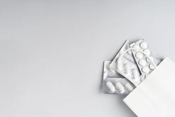 Packs of white pills in white eco bag on gray background, top view. Different medicines, tablets, medicine capsules. Medicine concept, background. Text place