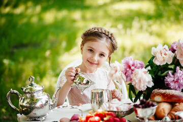 Little girl drinks tea in the park