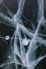 Frozen Baikal lake with cracks and methane bubbles on the transparent ice surface. Winter abstract...