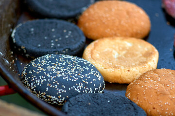 black and yellow hamburger buns in a frying pan, close-up, street food