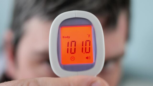 Man with 101 Degrees Fever taking temperature with infrared thermometer