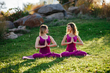 two young female friends do sports and yoga in the park