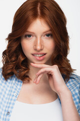 Fototapeta premium pensive young redhead woman in blue plaid shirt biting lips isolated on white.
