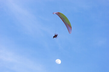 Paraglider in the blue sky with moon