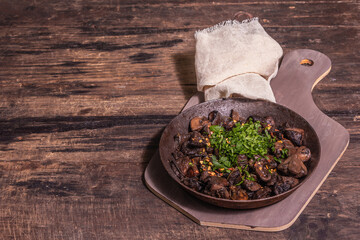 Fried royal champignons in an old cast-iron skillet with trendy hard light, dark shadow