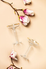 Spring magnolia flowers and wine glasses flat lay, top view