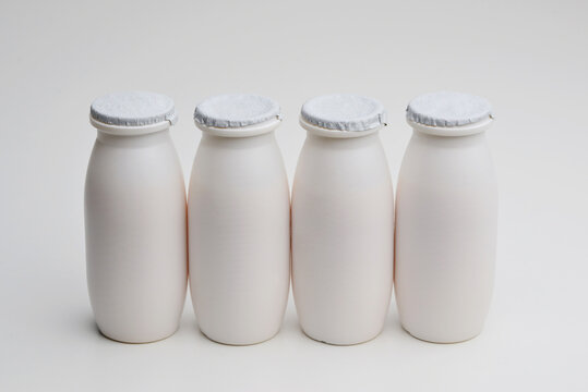 Natural liquid yogurt with probiotics in small plastic bottles on white background. Healthy, balanced diet food, healthy breakfast, dairy products. Selective soft focus, blurred background.