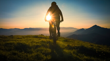 Silhouette of a woman on mountain bike looking at sunset