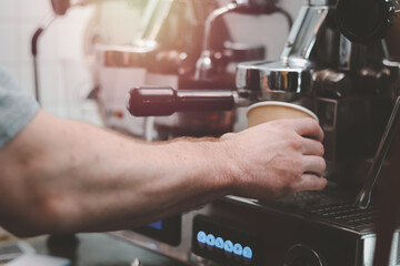 Close up of barista hands preparing hot coffee, waiter staff working with coffee machine in coffee shop counter bar.