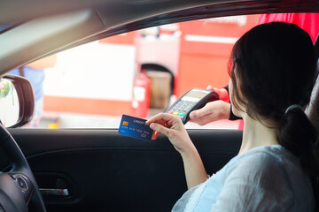 Customer woman holding credit card (mock up) for payment at gas station, young beautiful lady in...