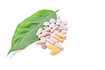 Kinds of vitamins and tablets on a green leaf isolated on a white background.