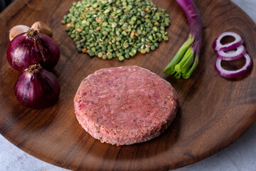 vegan and vegetarian black bean burger with raw peas beet green onion garlic purple onion pepper on wooden plate for healthy eating