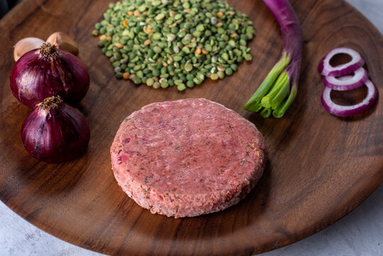vegan and vegetarian black bean burger with raw peas beet green onion garlic purple onion pepper on wooden plate for healthy eating - Powered by Adobe