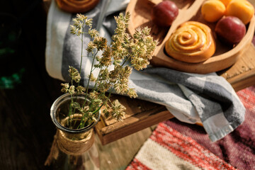 Summer grass field in close-up sunlight. Fruits and pastries on a beach blanket.
