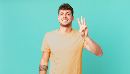 handsome man smiling and looking friendly, showing number three or third with hand forward,...