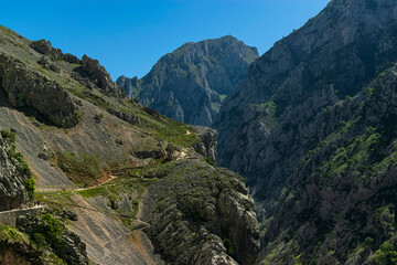 Fototapeta na wymiar A dangerous route ascends through the spectacular valley between majestic rocky mountains. Photograph taken in the Picos de Europa, Asturias, Spain. 