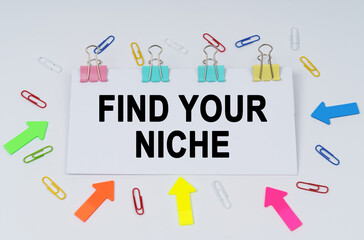 On the table there are paper clips and directional arrows, a sign that says - Find Your Niche