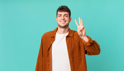 handsome man smiling and looking friendly, showing number three or third with hand forward,...