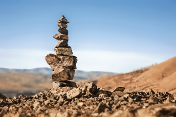 pyramid of stones stacked on top of each other against the background of mountains and the blue sky, the god of the mountain, the spirits of the mountains