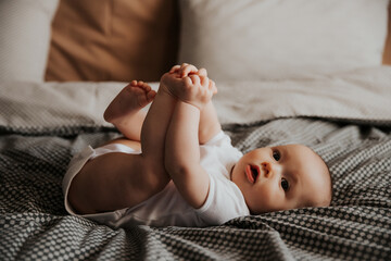 happy child lying on the bed and holding his legs