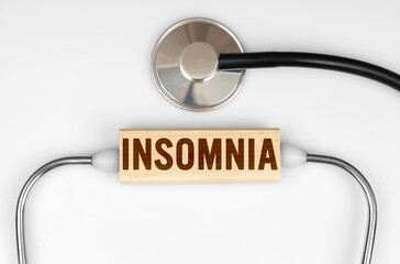 On the table is a stethoscope and a wooden plate with the inscription - INSOMNIA