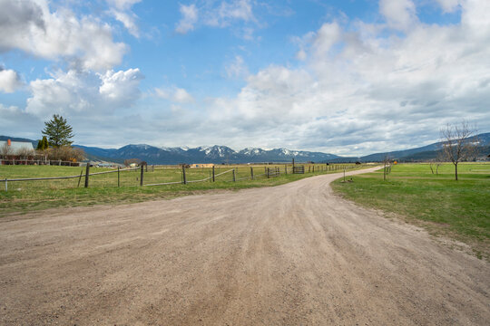 A Snow Covered Mountain Range Is Seen From A Rural Country Ranch And Dirt Road In The Small Town Of Arlee, Montana, USA