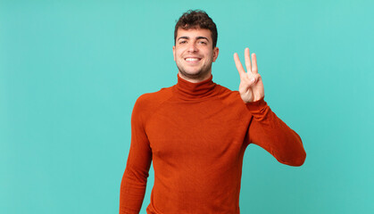 handsome man smiling and looking friendly, showing number three or third with hand forward,...