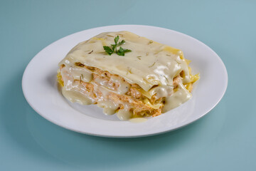 Chicken lasagna in white dish isolated on neutral background.