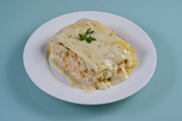 Chicken lasagna in white dish isolated on neutral background.