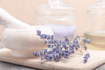 Herbal oil, salt and lavender flowers on a wooden background
