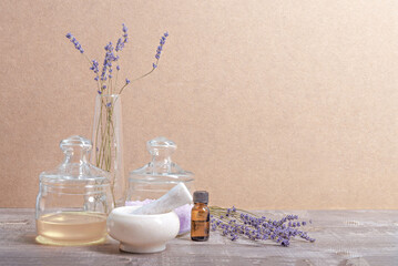 Herbal oil, salt and lavender flowers on a wooden background